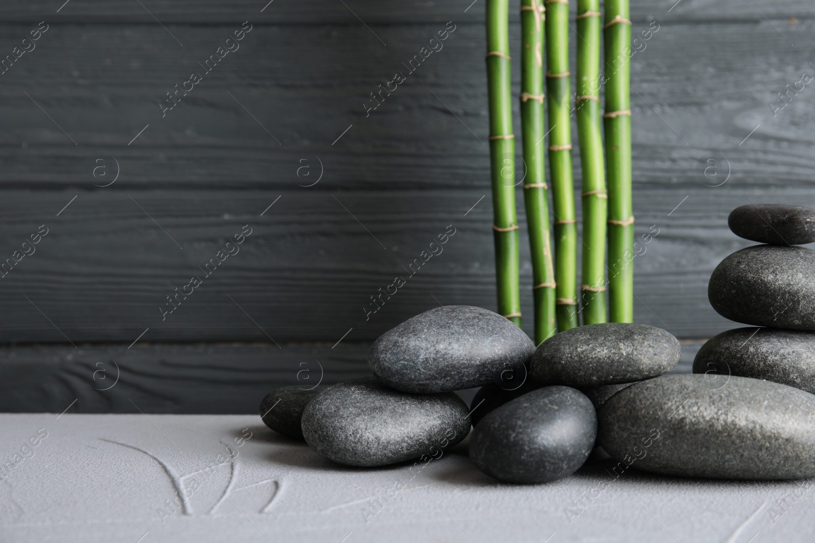 Photo of Zen stones and bamboo on table against wooden background. Space for text