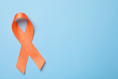 Photo of Orange ribbon on light blue background, top view with space for text. Multiple sclerosis awareness