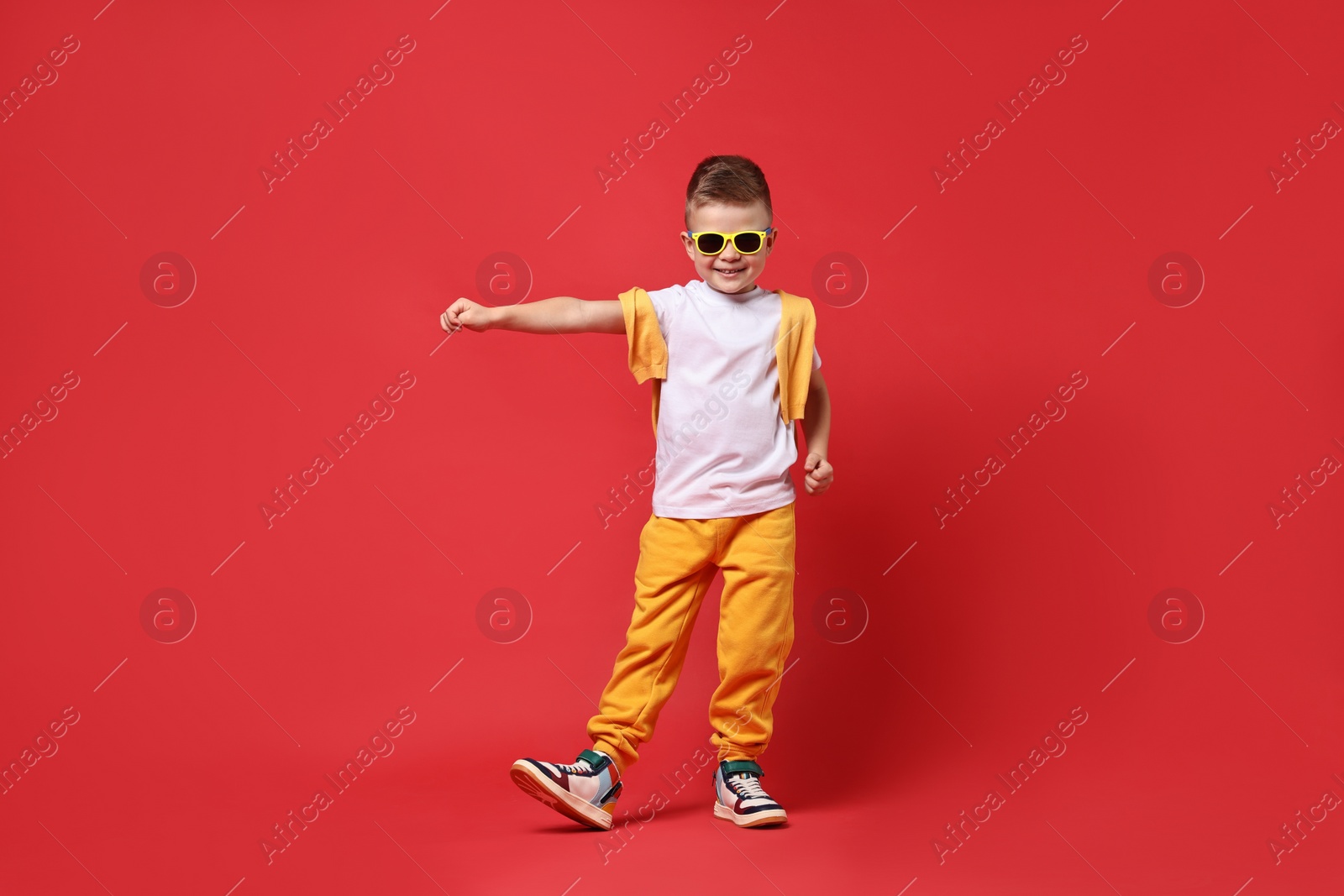 Photo of Happy little boy dancing on red background