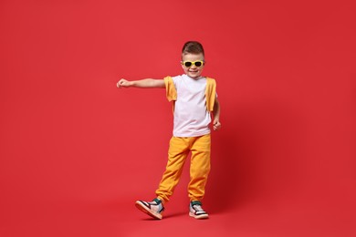 Happy little boy dancing on red background