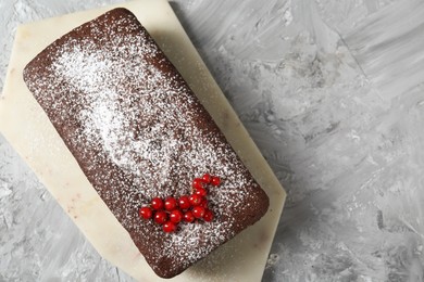 Photo of Tasty chocolate sponge cake with powdered sugar and currant on light grey textured table, top view. Space for text