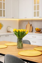 Photo of Spring interior. Bouquet of beautiful yellow tulips on wooden table in stylish kitchen
