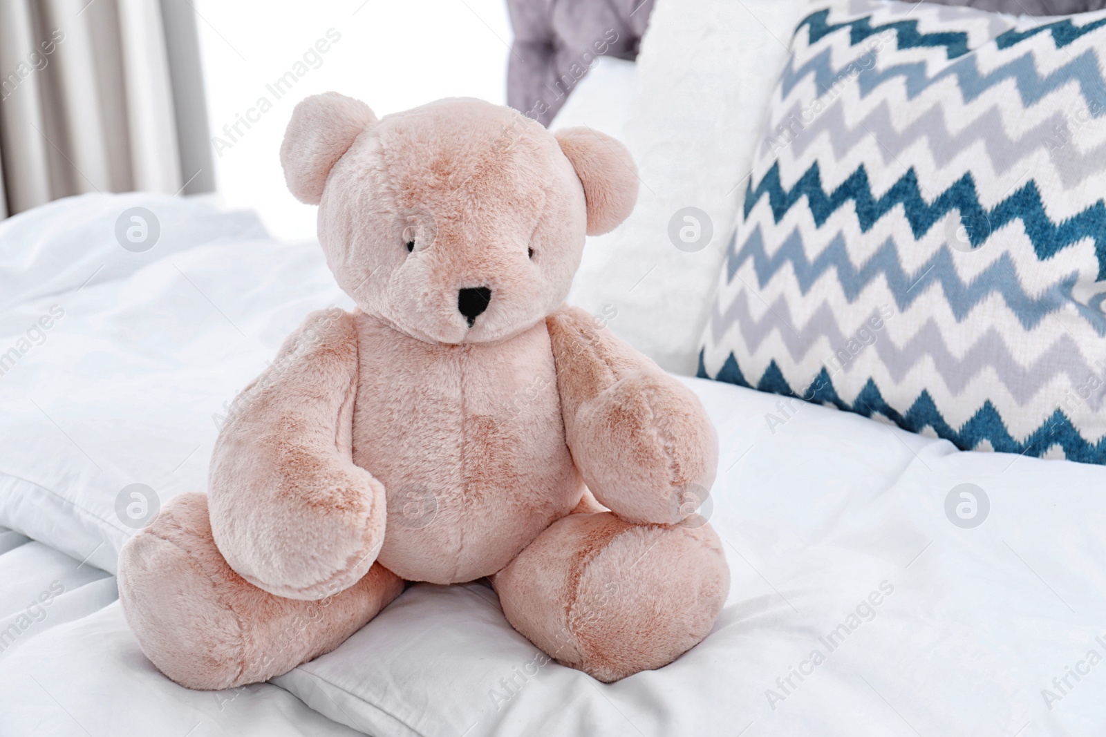 Photo of Cute teddy bear sitting on bed indoors. Space for text