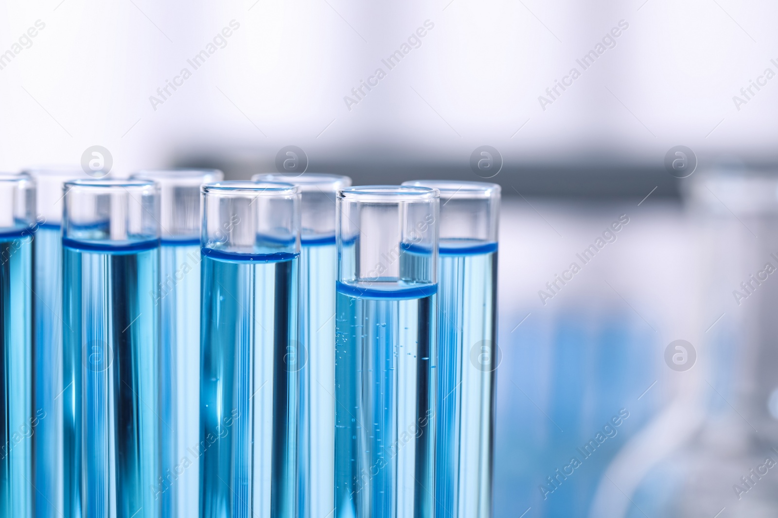 Photo of Test tubes with reagents on blurred background, closeup. Laboratory analysis