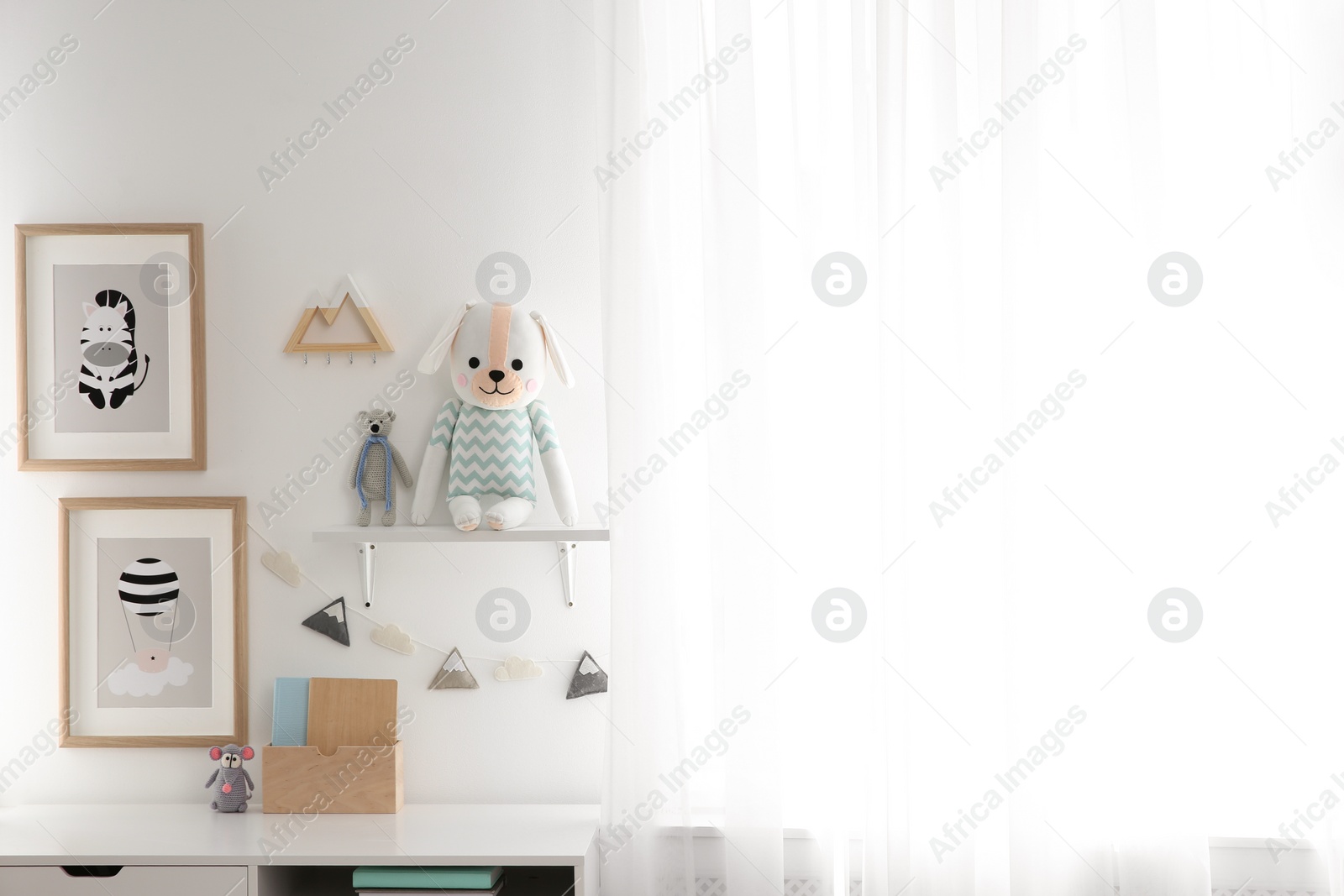 Photo of Stylish child's room interior with desk and beautiful pictures. Space for text