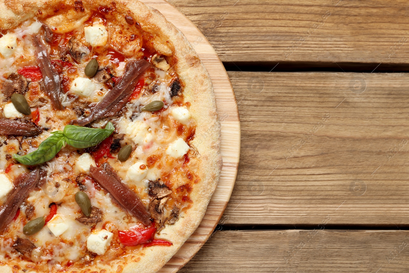 Photo of Tasty pizza with anchovies, basil and olives on wooden table, top view. Space for text