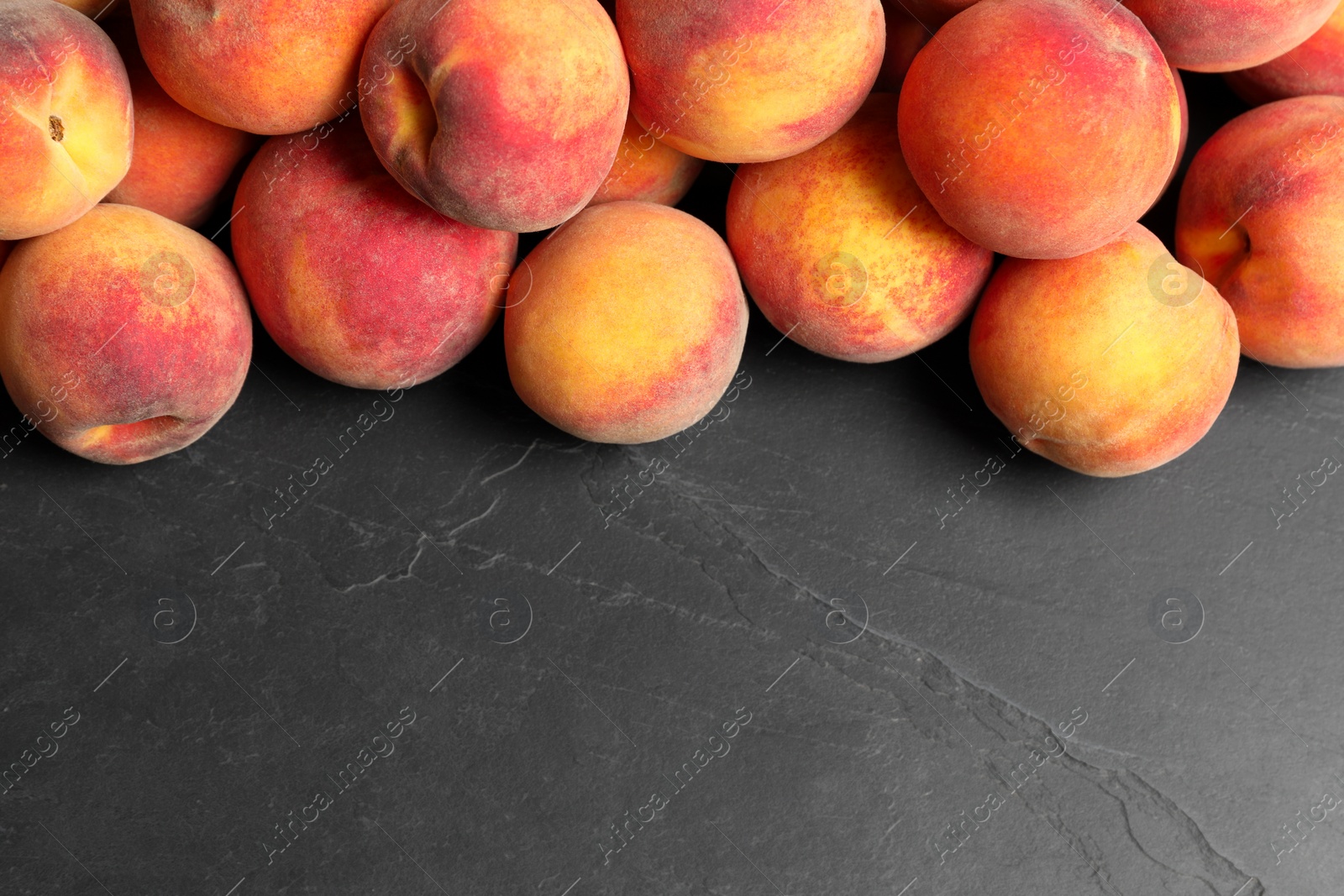 Photo of Fresh peaches on dark grey textured table, top view. Space for text