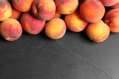 Fresh peaches on dark grey textured table, top view. Space for text