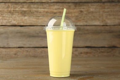 Plastic cup of tasty smoothie on wooden table