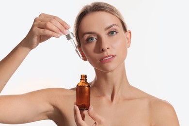 Beautiful woman with cosmetic serum in her hands on white background