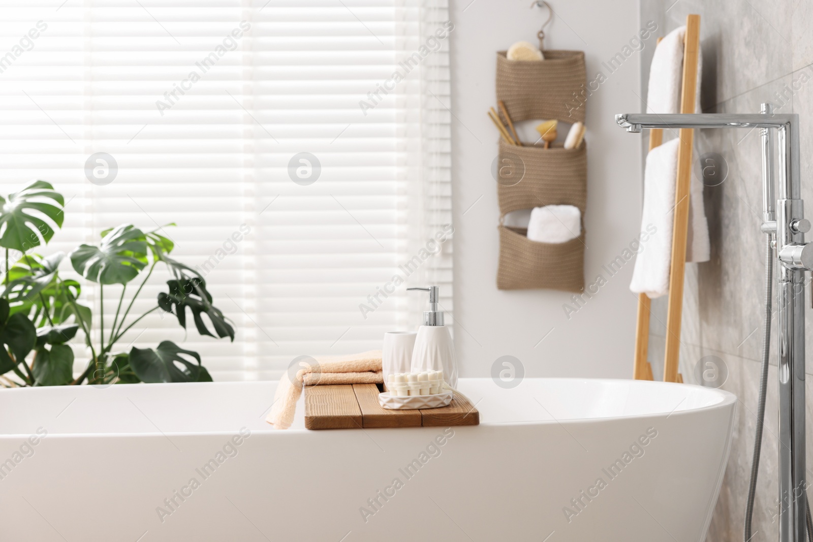 Photo of Set of different bath accessories and soap on tub in bathroom