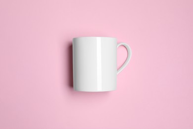 Photo of White ceramic mug on pink background, top view