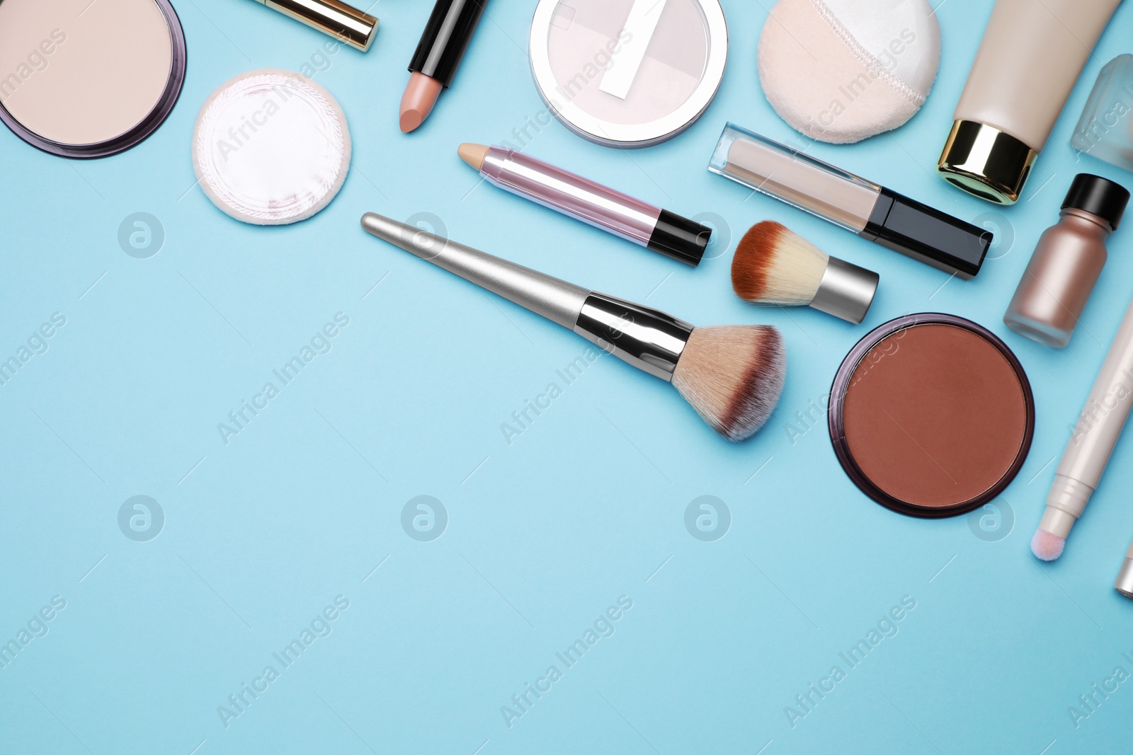 Photo of Face powders and other decorative cosmetic products on light blue background, flat lay. Space for text