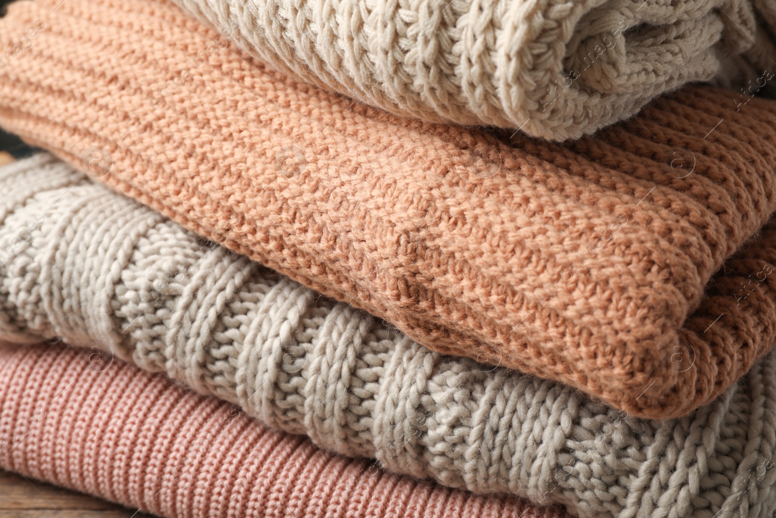 Photo of Stack of folded warm knitted sweaters, closeup