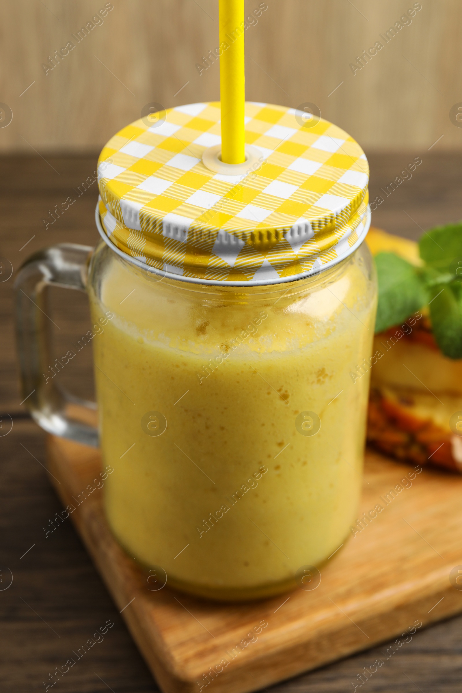 Photo of Tasty pineapple smoothie and sliced fruit on wooden table, closeup