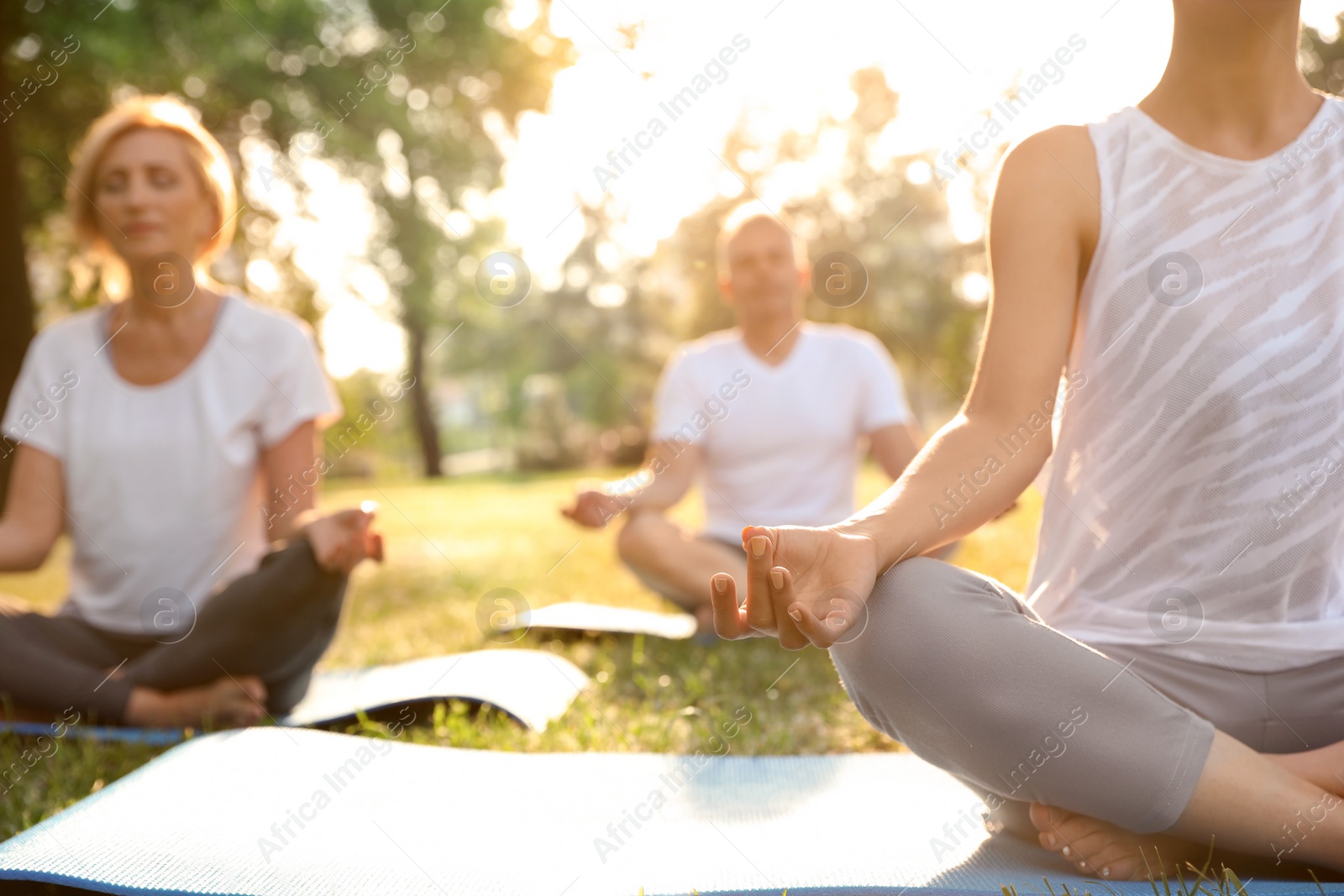 Photo of People practicing yoga in park at morning, closeup