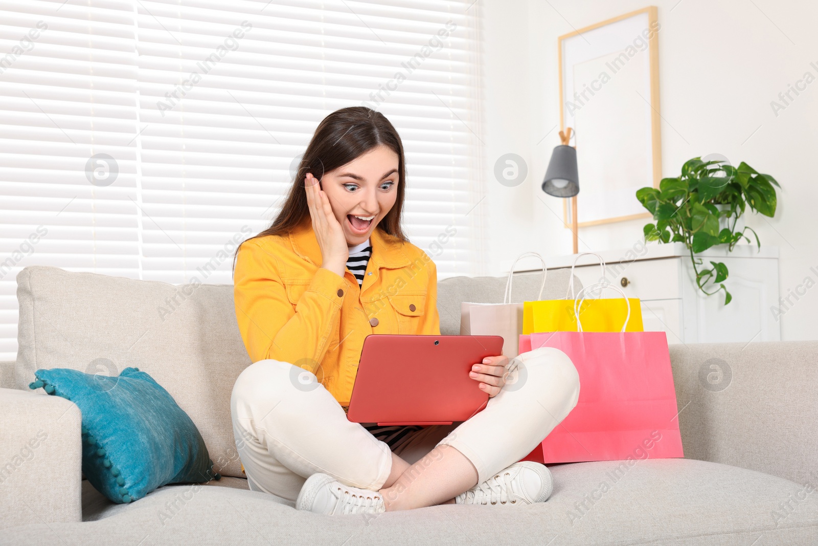 Photo of Special Promotion. Emotional woman looking at laptop on sofa indoors