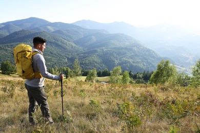 Photo of Tourist with backpack and trekking poles enjoying mountain landscape, space for text