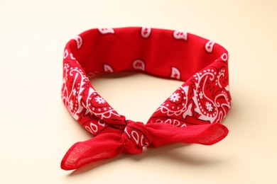 Photo of Tied red bandana with paisley pattern on beige background