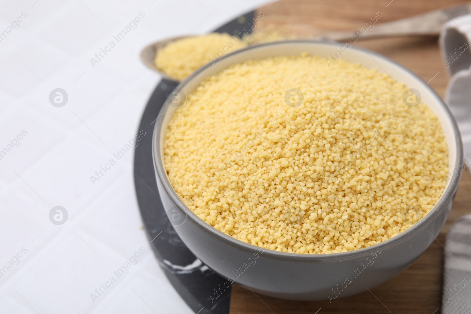 Photo of Raw couscous in bowl on table, closeup