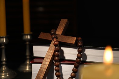 Church candles, Bible, rosary beads and cross on table