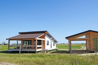 Photo of Wooden house and barn in countryside on sunny day