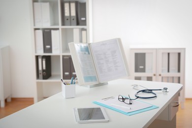 Photo of Doctor's workplace with tablet and stationery in medical office