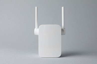 Photo of New modern Wi-Fi repeater on light gray background