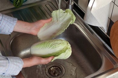 Photo of Woman washing fresh Chinese cabbage in sink, closeup