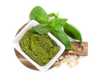 Photo of Fresh tasty pesto sauce, pine nuts and basil isolated on white, top view