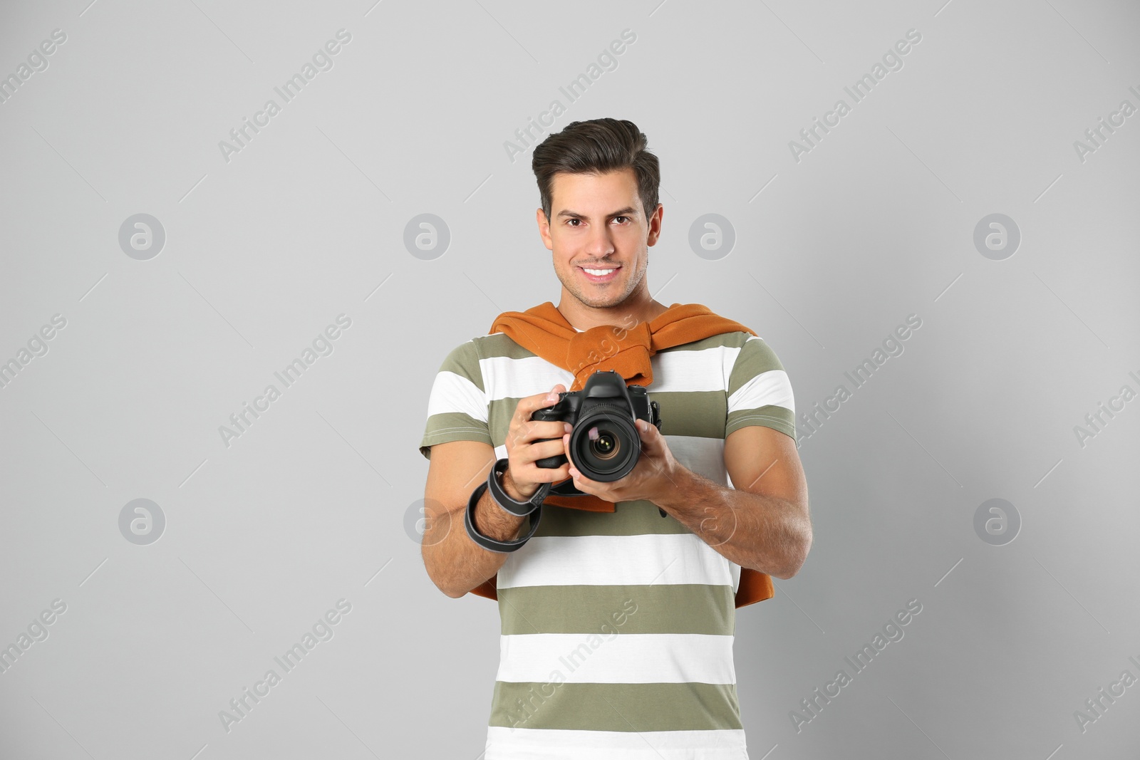 Photo of Professional photographer working on light grey background in studio