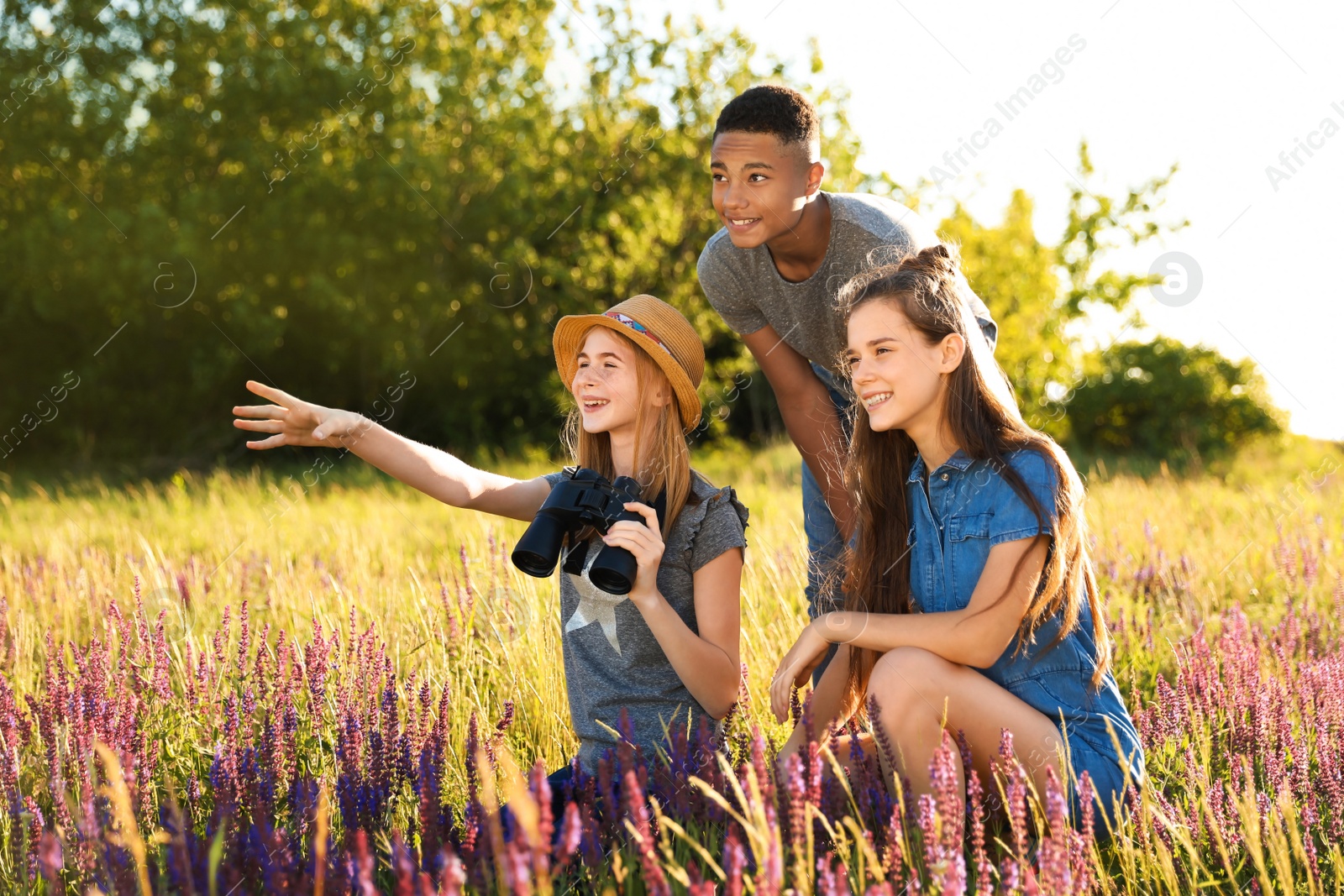 Photo of Group of children with binoculars in field. Summer camp