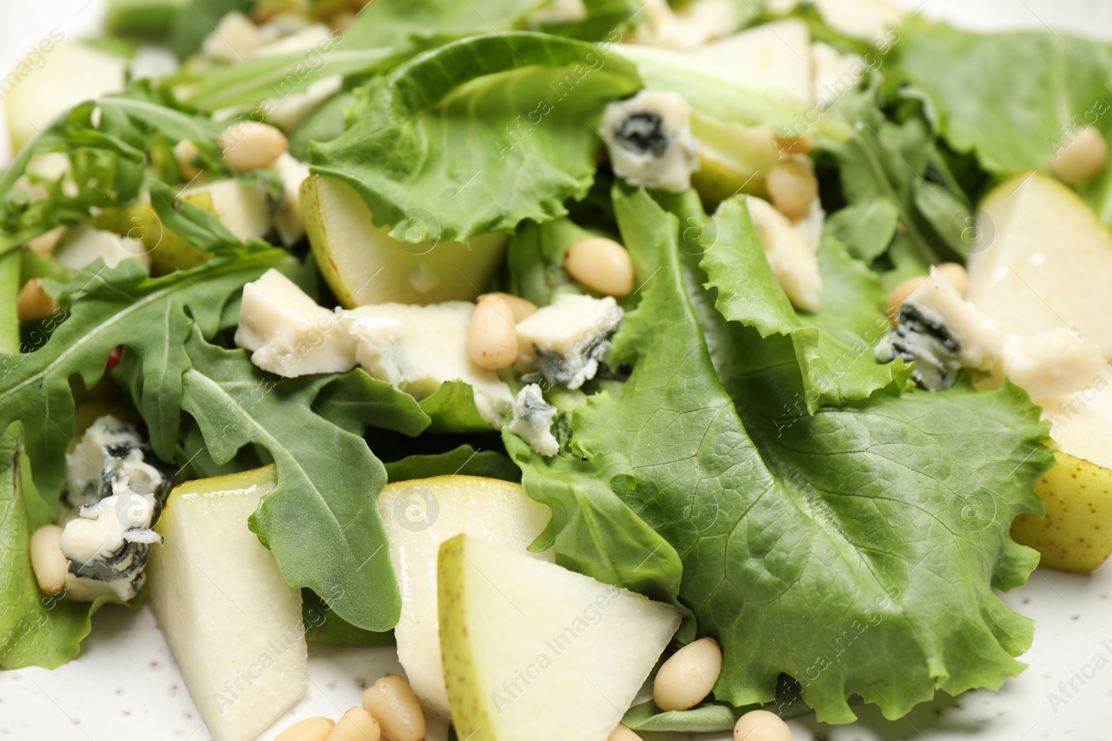 Photo of Tasty salad with pear slices, lettuce and pine nuts as background, closeup