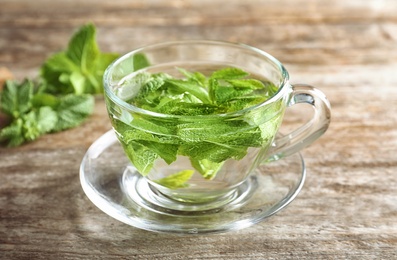 Photo of Cup with hot aromatic mint tea on wooden table