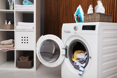 Photo of Laundry room interior with washing machine near wooden wall