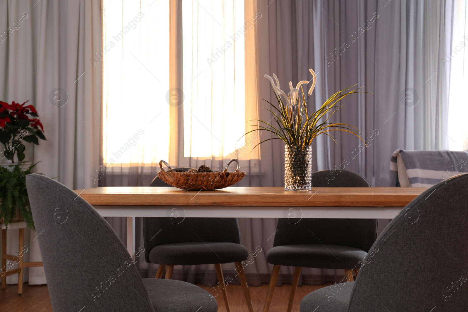 Photo of Vase on wooden table near window with curtains in room