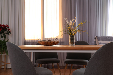 Photo of Vase on wooden table near window with curtains in room