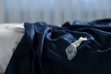 Photo of Unrolled condom on bed in bedroom. Safe sex