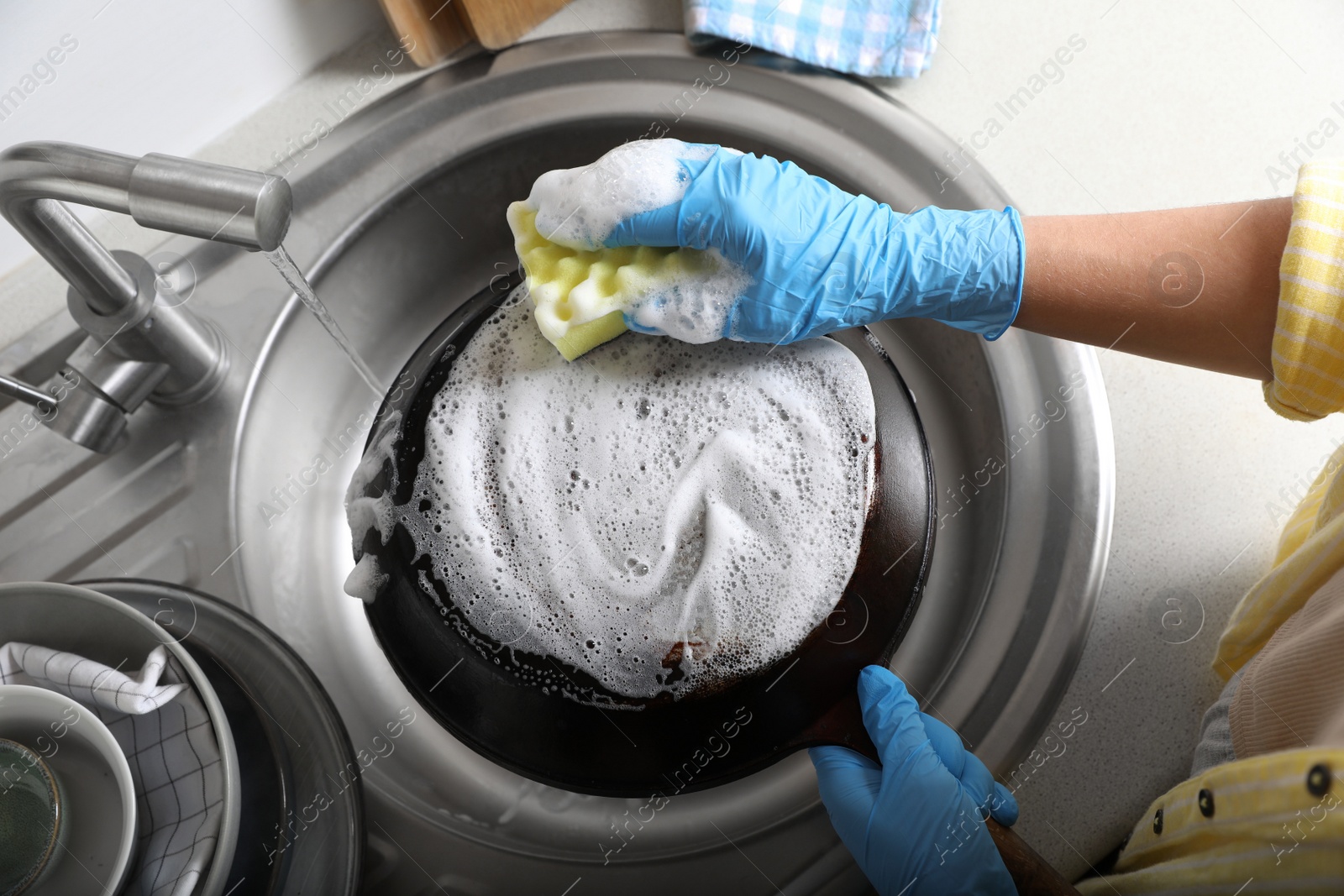 Photo of Woman washing dirty frying pan in sink, above view