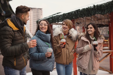 Friends with cups of mulled wine at winter fair