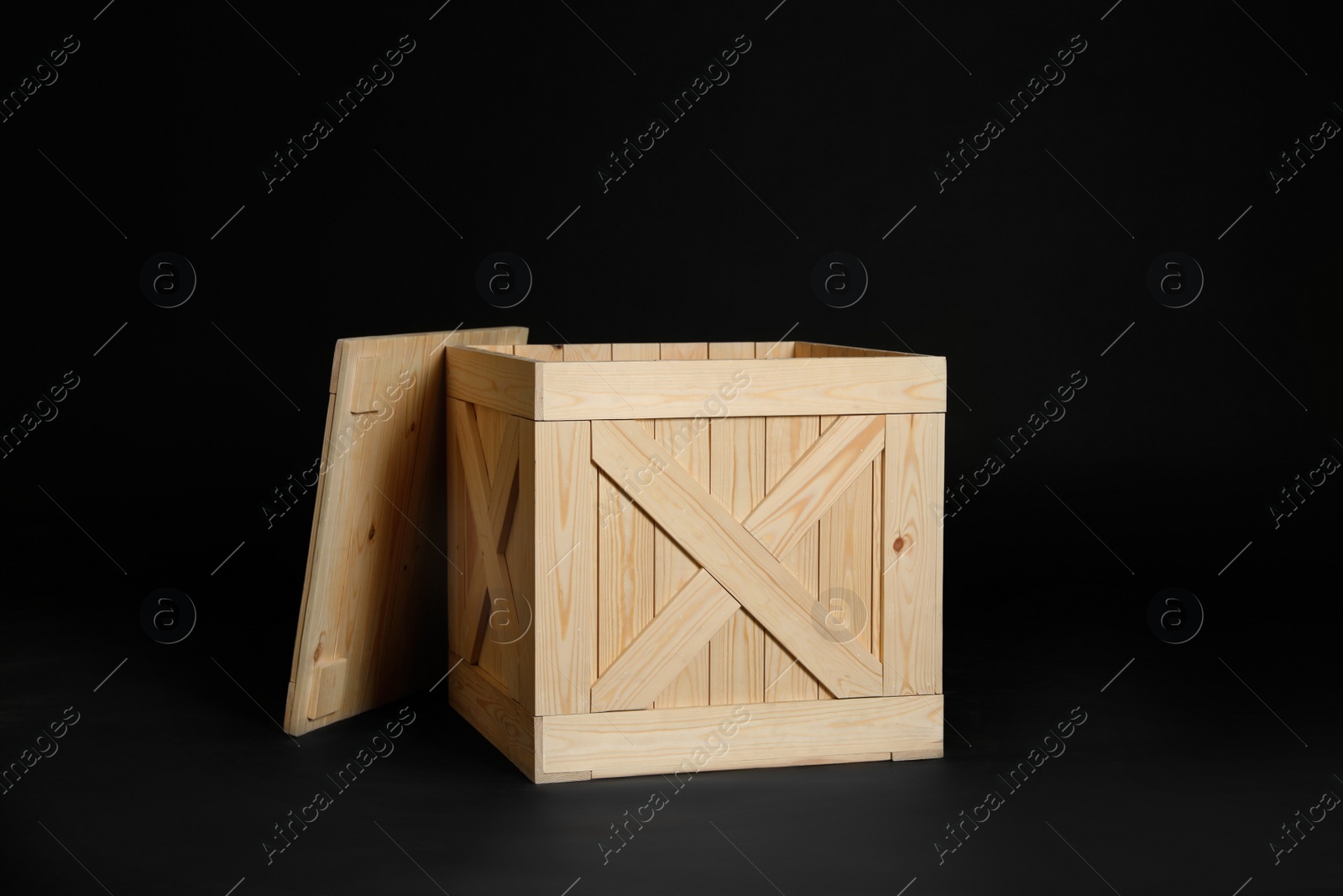 Photo of One open wooden crate on black background