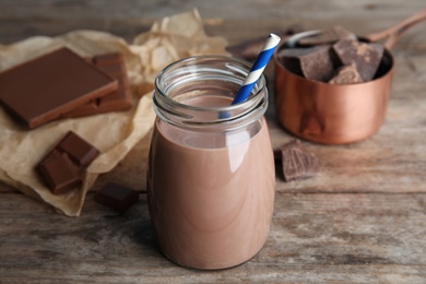 Jar with tasty chocolate milk on wooden table. Dairy drink