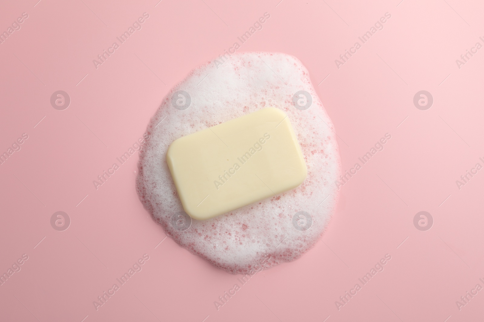 Photo of Soap with fluffy foam on pink background, top view