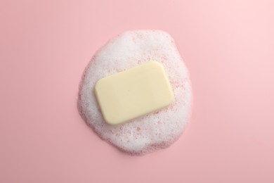 Soap with fluffy foam on pink background, top view