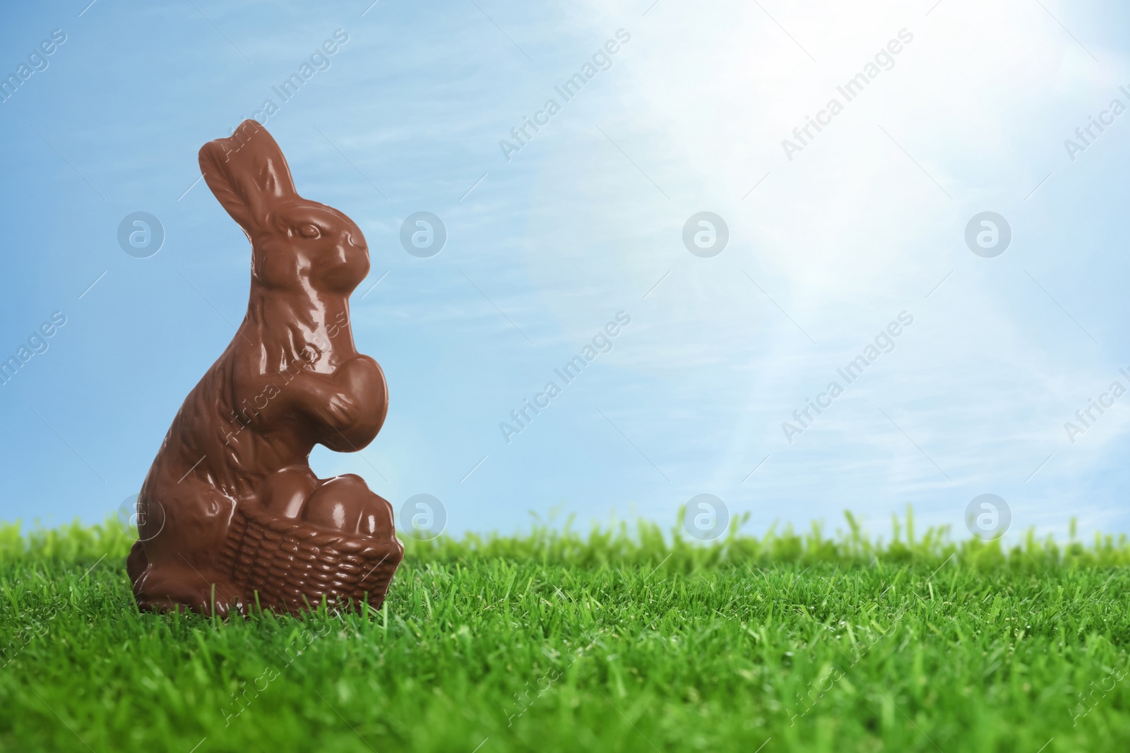 Image of Chocolate bunny on green grass outdoors, space for text. Easter celebration