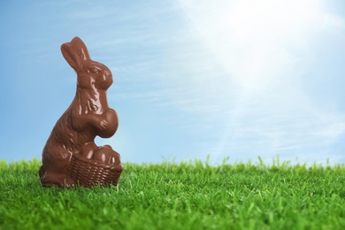 Image of Chocolate bunny on green grass outdoors, space for text. Easter celebration