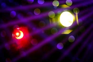 Bright spotlights and beams of light in night club, bokeh effect