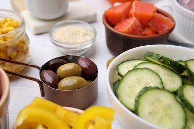 Photo of Ingredients for poke bowl on white checkered table, closeup