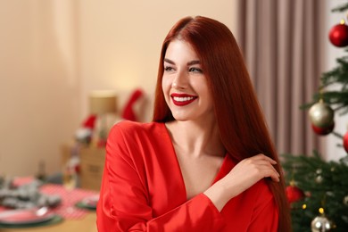 Photo of Beautiful young woman near Christmas tree at home, space for text