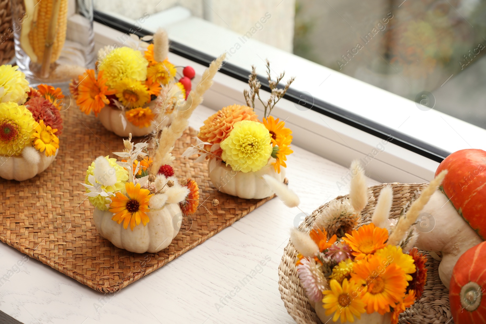 Photo of Composition with small pumpkins, beautiful flowers and spikelets on white wooden window sill indoors